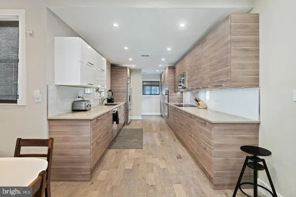 a large kitchen with stainless steel appliances kitchen island a large counter top a stove a chimney a sink and cabinets