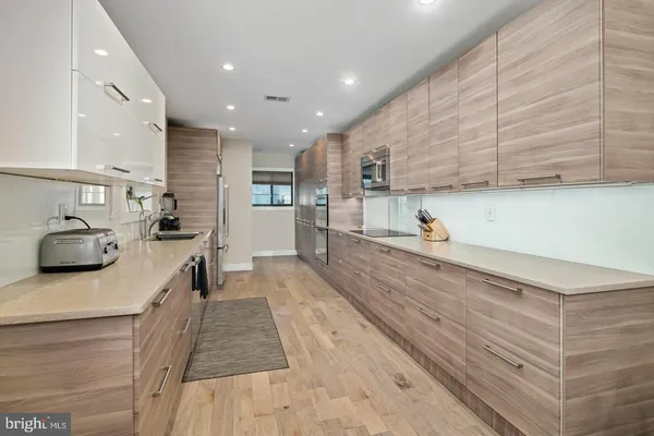 a view of a kitchen with kitchen island a sink wooden floor and stainless steel appliances
