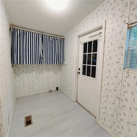 a view of a livingroom with wooden floor and kitchen space