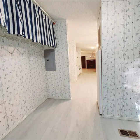 an empty room with a chandelier fan and windows