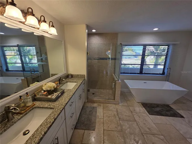 a bathroom with a granite countertop sink a toilet a mirror and shower