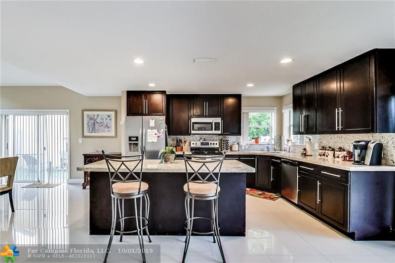 Kitchen has it all, open concept, stunning floors that accent the dark wood cabinets and recessed lighting. There are two sliders off the kitchen one from the dining and one to the right from the family room.