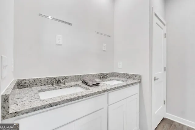 a bathroom with a granite countertop sink and white cabinets