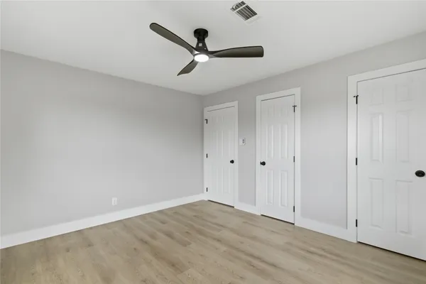 an empty room with wooden floor and ceiling fan