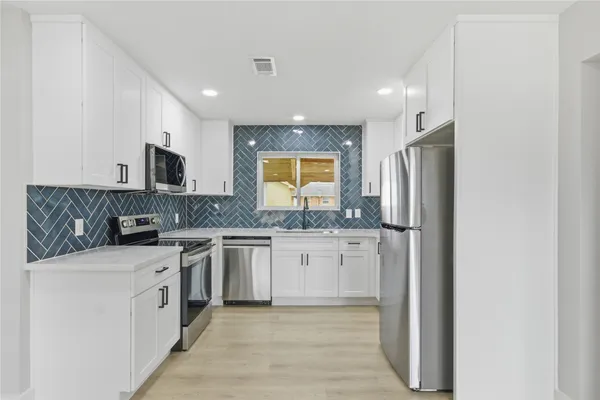 a large kitchen with stainless steel appliances granite countertop a stove a sink and a refrigerator