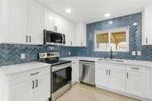 a kitchen with white cabinets sink and stainless steel appliances