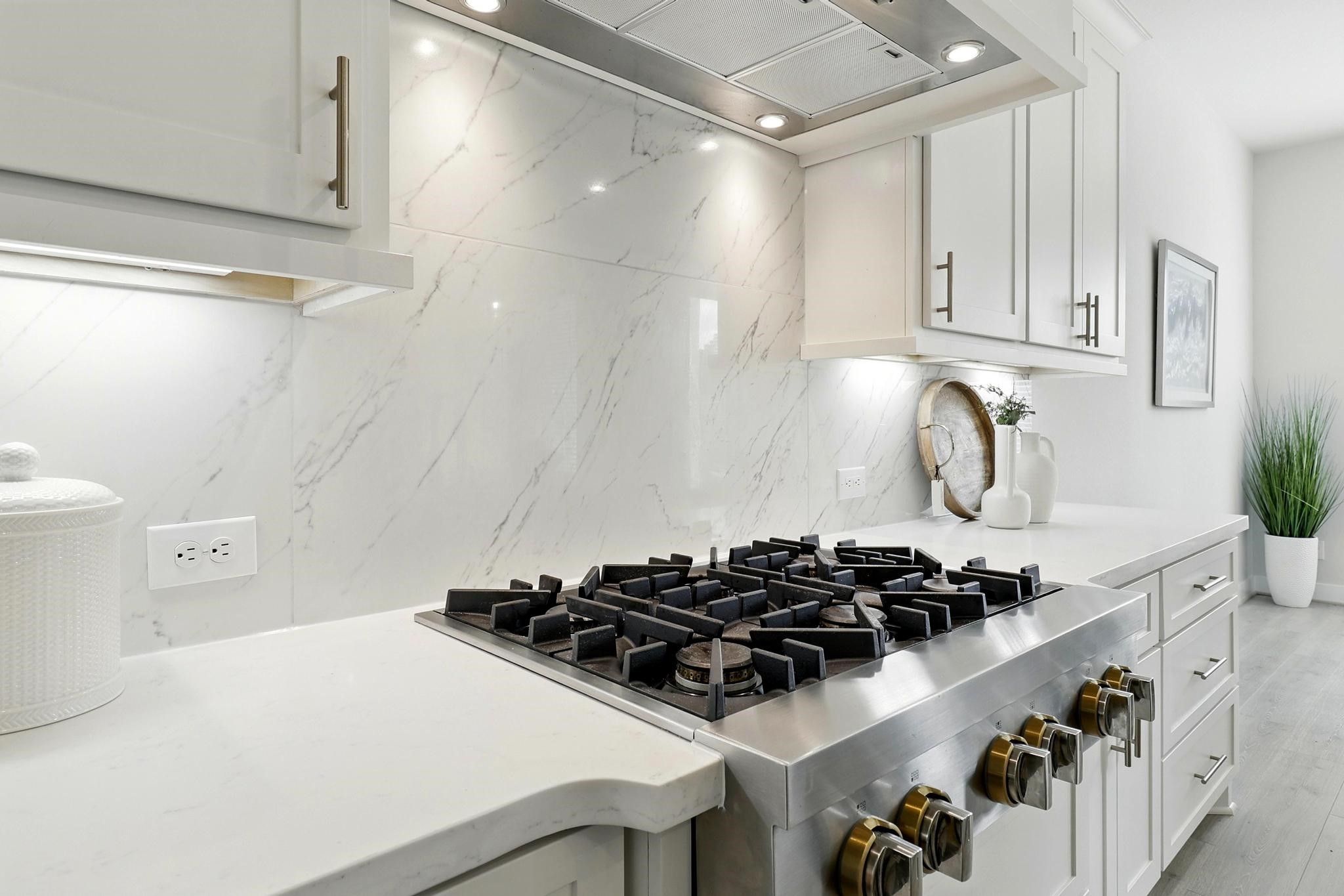 26923 Arethusa Court Spring, TX 77389 - Photo 10 of 44 Modern kitchen with gas upgraded cooktop , white cabinetry, gorgeous backsplash, and quartz countertops, creating a clean and elegant look.