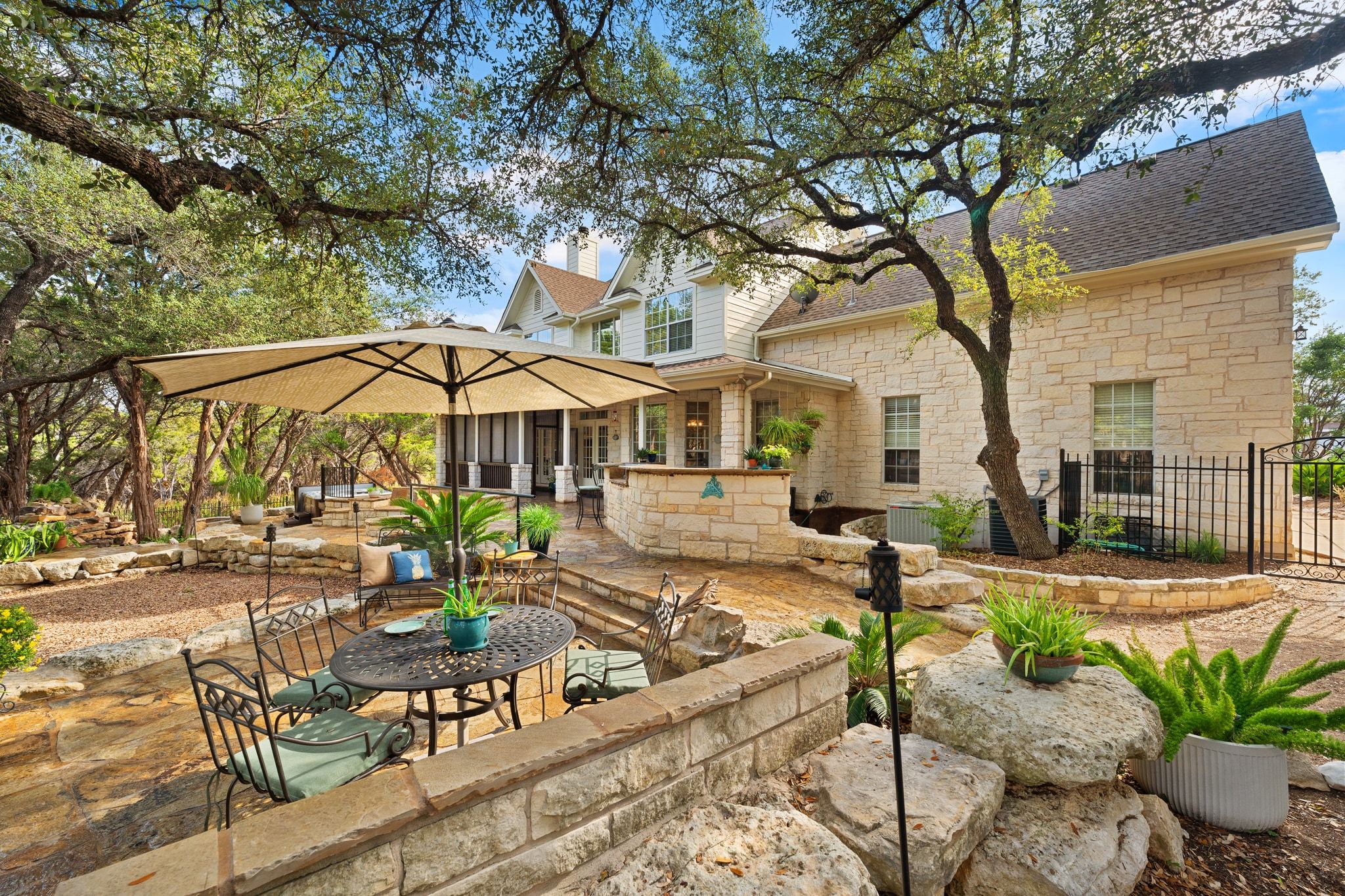 19045 Venture Drive Lago Vista, TX 78645 - Photo 28 of 40 Rear view of house with a patio area, stone siding, and a shingled roof