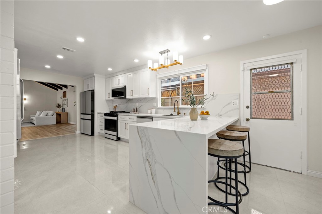 12817 Meadow Green Road La Mirada, CA 90638 - Photo 13 of 43 a kitchen with stainless steel appliances kitchen island granite countertop a sink and cabinets