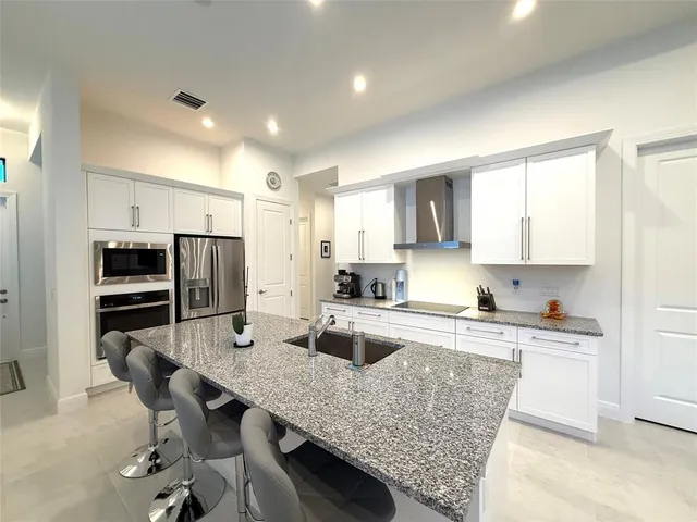 a kitchen with stainless steel appliances a dining table chairs sink refrigerator and cabinets