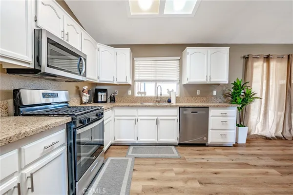 a kitchen with stainless steel appliances granite countertop a refrigerator a microwave a stove and a dining table with wooden floor