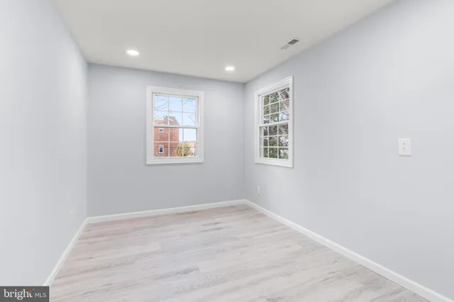 a view of an empty room with wooden floor and windows