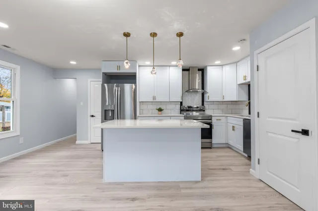 a kitchen with stainless steel appliances granite countertop a stove a sink dishwasher a refrigerator white cabinets and wooden floor