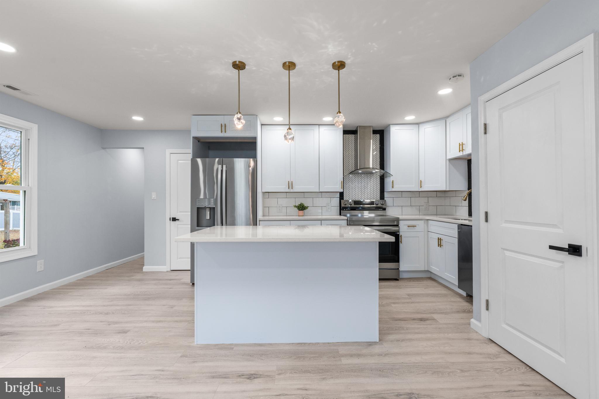11046 Ferndale Street Philadelphia, PA 19116 - Photo 6 of 37 a large kitchen with stainless steel appliances kitchen island granite countertop a stove a sink a refrigerator and white cabinets with wooden floor