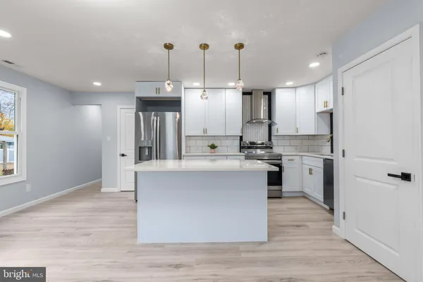 a kitchen with stainless steel appliances granite countertop a stove a sink dishwasher a refrigerator white cabinets and wooden floor
