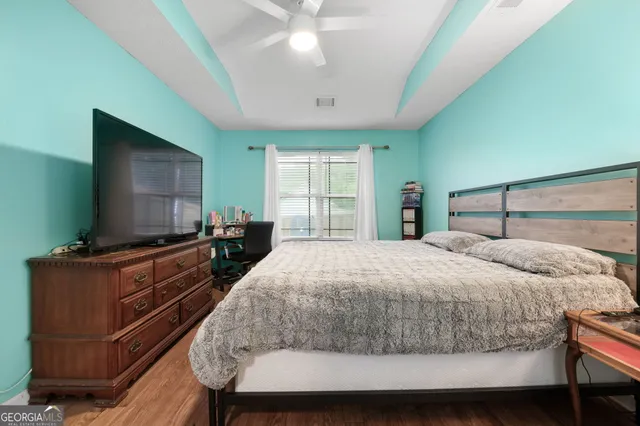 a bedroom with a large bed and a flat tv screen on dresser
