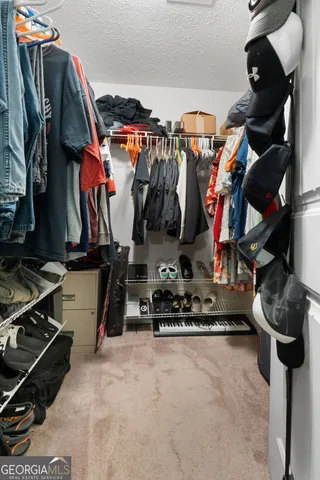 a view of walk in closet with clothes and shoes