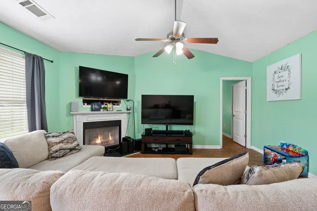 a living room with fireplace a flat screen tv and a window