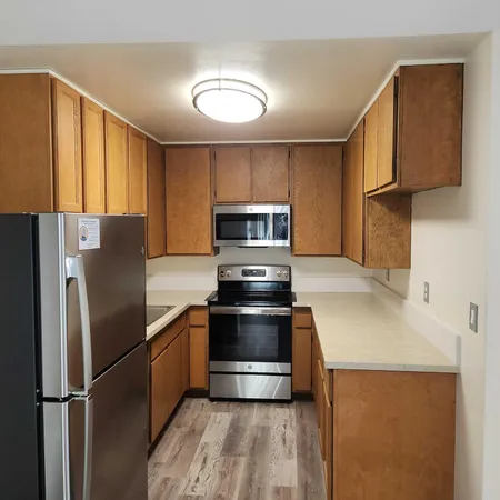 a kitchen with stainless steel appliances granite countertop a refrigerator a stove and a sink with wooden floors