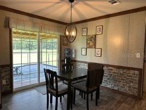 a dining room with wooden floor a chandelier a wooden table and chairs