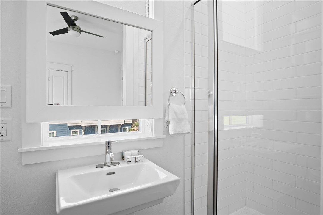 214 Sunset Avenue, Unit 2 Port Aransas, TX 78373 - Photo 14 of 37 a bathroom with a sink a mirror and a shower