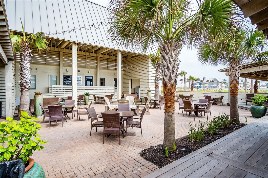 214 Sunset Avenue, Unit 2 Port Aransas, TX 78373 - Photo 22 of 37 a view of a patio with table and chairs potted plants and palm tree