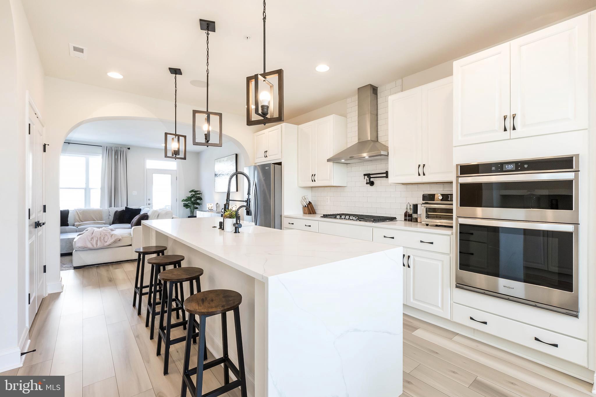 1096 Holden Road Frederick, MD 21701 - Photo 5 of 51 a open kitchen with stainless steel appliances kitchen island granite countertop a stove a sink and white cabinets with wooden floor