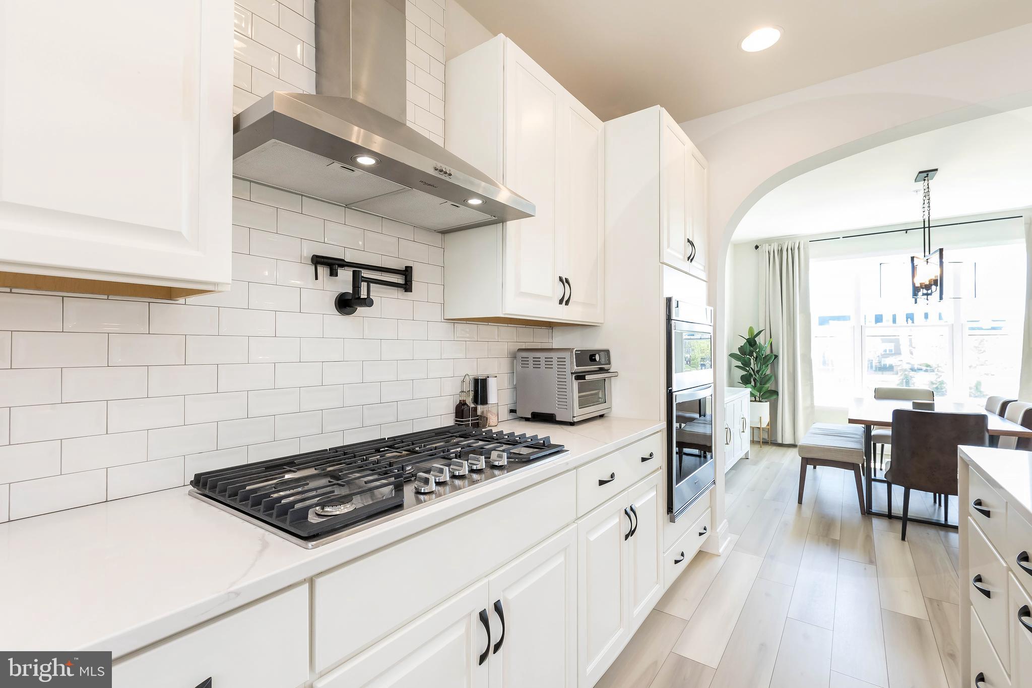 1096 Holden Road Frederick, MD 21701 - Photo 7 of 51 a kitchen with a stove a sink a dining table and chairs