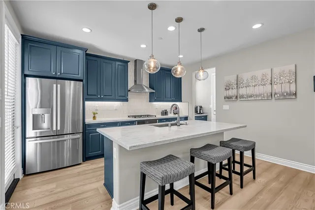 a kitchen with granite countertop a sink a center island a refrigerator and wooden floor