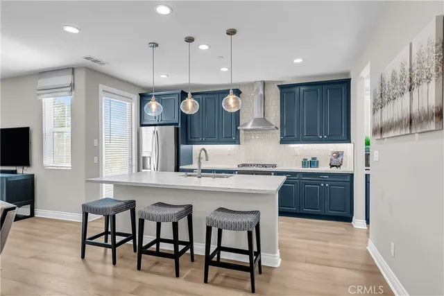 a kitchen with stainless steel appliances granite countertop a stove top oven a refrigerator a sink and chairs