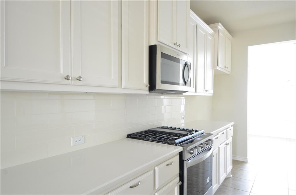 14403 McCoy Loop Austin, TX 78717 - Photo 9 of 29 White cabinetry and subway tile backsplash complete this sleek, well-appointed kitchen.