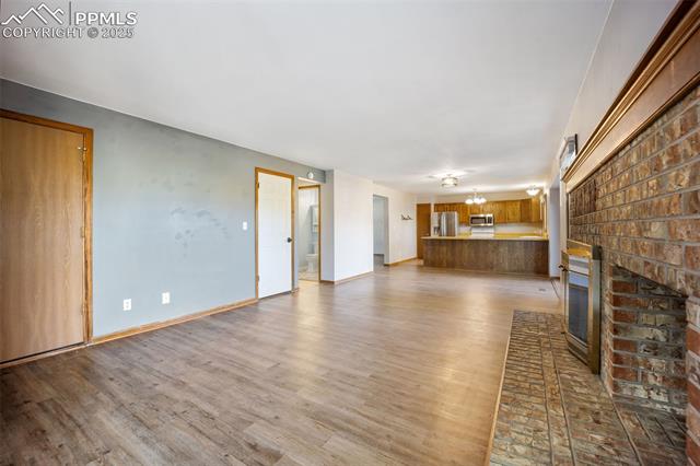 103 Saddlemountain Road Colorado Springs, CO 80919 - Photo 5 of 30 Unfurnished living room with a brick fireplace and light wood-style flooring