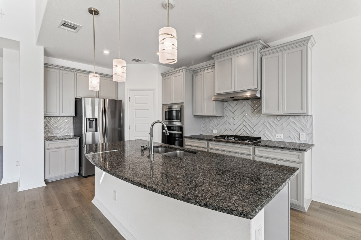 20520 Carries Ranch Road Pflugerville, TX 78660 - Photo 6 of 32 a kitchen with stainless steel appliances granite countertop a sink a refrigerator and a stove top oven