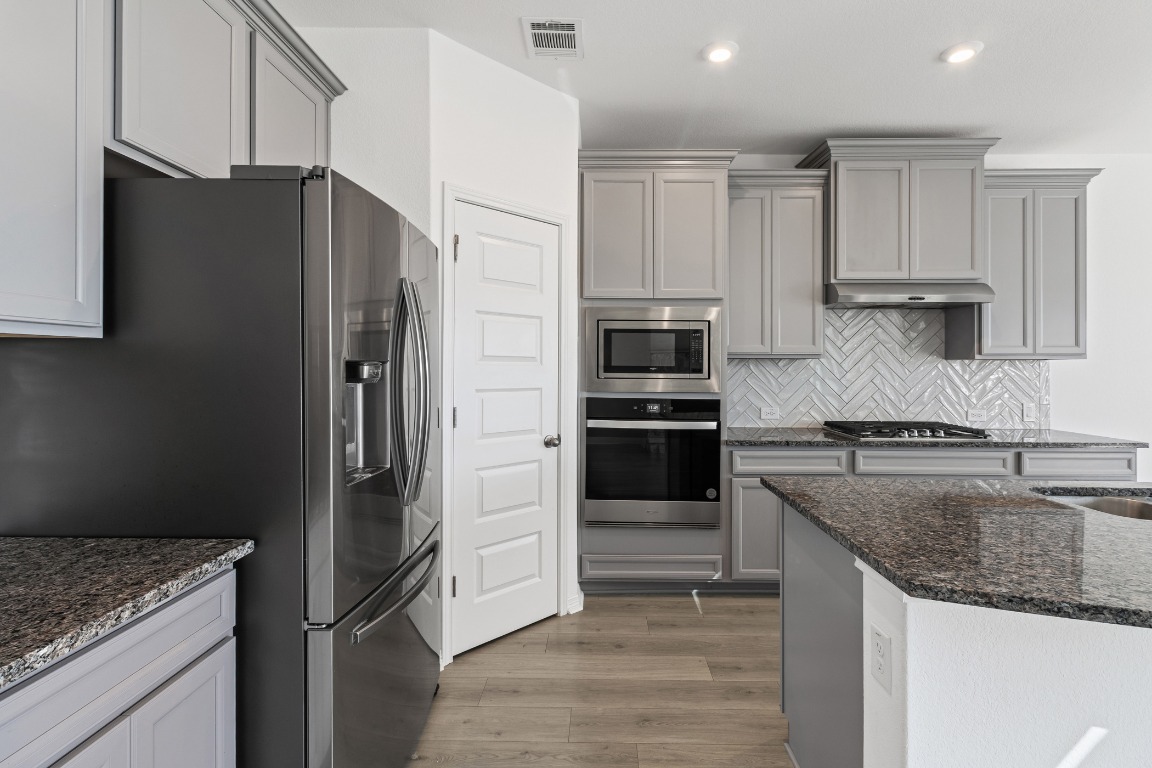 20520 Carries Ranch Road Pflugerville, TX 78660 - Photo 8 of 32 a kitchen with granite countertop a refrigerator and a sink
