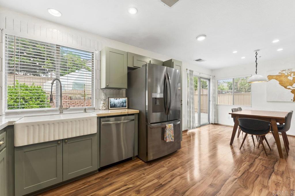 305 Cobblestone Place Santee, CA 92071 - Photo 11 of 41 a kitchen with stainless steel appliances granite countertop a refrigerator a stove a sink dishwasher with a dining table and chairs with wooden floor