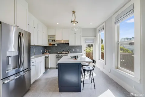 a kitchen with stainless steel appliances a refrigerator a stove a sink and white cabinets