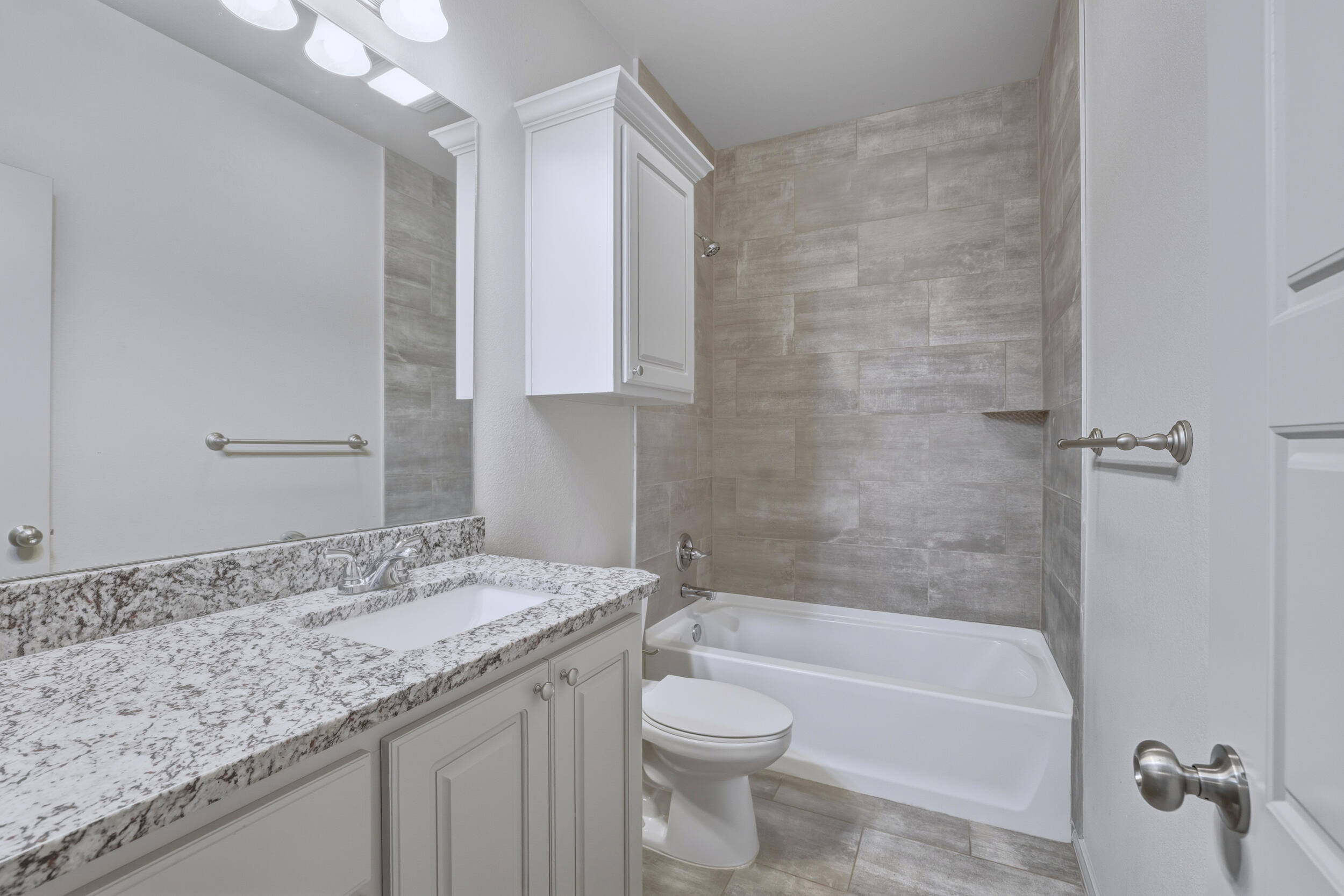 7103 22nd Street Lubbock, TX 79407 - Photo 25 of 30 a bathroom with a granite countertop sink a toilet and bathtub