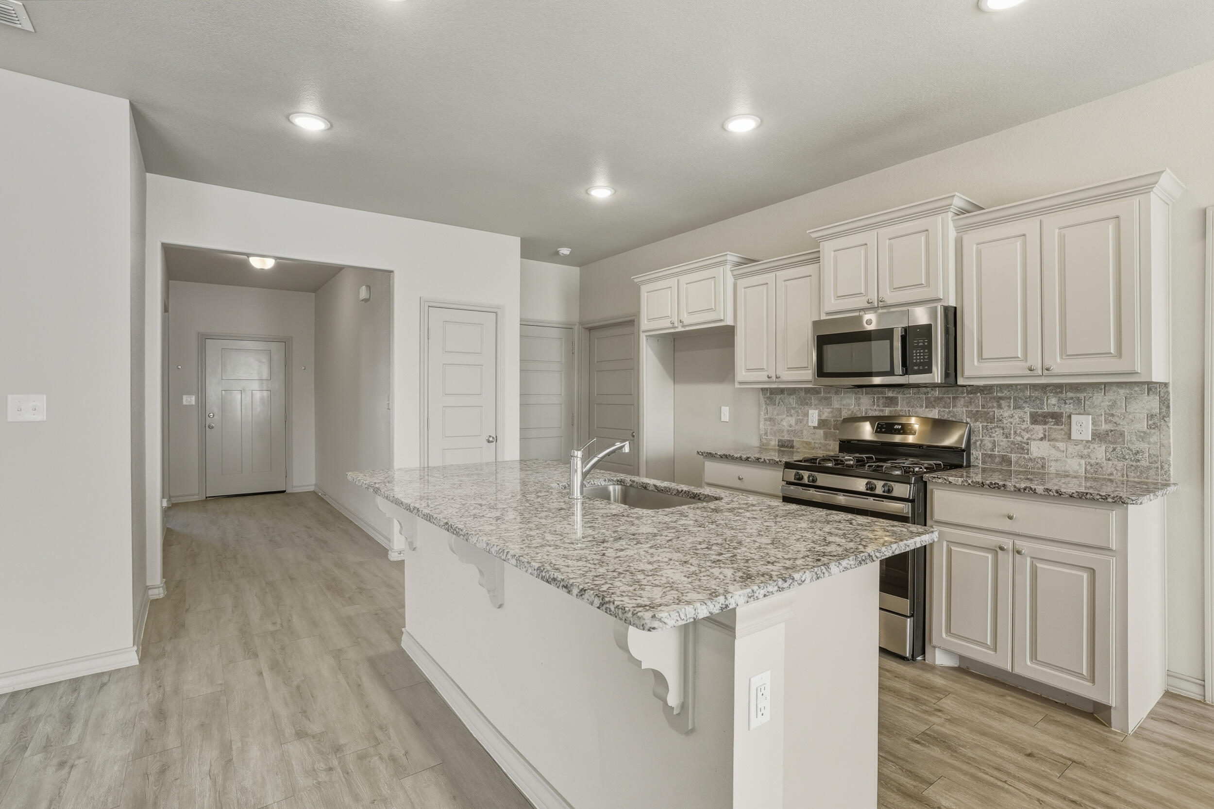 7103 22nd Street Lubbock, TX 79407 - Photo 8 of 30 a kitchen with stainless steel appliances granite countertop a sink stove microwave and cabinets