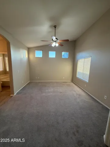 an empty room with windows and ceiling fan