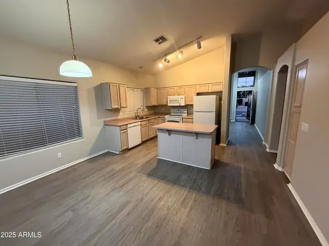 a kitchen with stainless steel appliances granite countertop a refrigerator a sink dishwasher a stove and white countertops with wooden floor