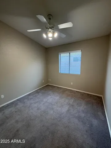 an empty room with a ceiling fan and window