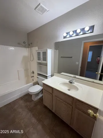 a spacious bathroom with a double vanity sink a toilet a mirror and shower