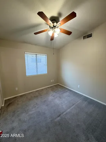 an empty room with a ceiling fan and window