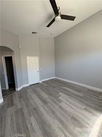 an empty room with wooden floor cabinet and windows
