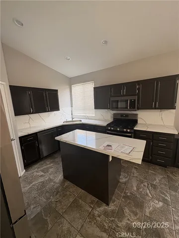 a kitchen with granite countertop a stove a microwave and wooden cabinets