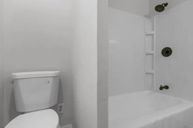 a white toilet sitting next to a bath tub