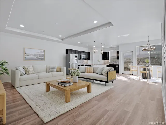 a view of an empty room with wooden floor and kitchen
