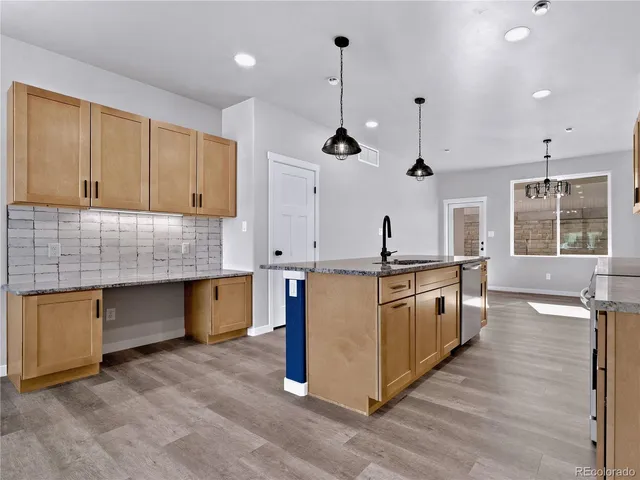 a kitchen with stainless steel appliances granite countertop a sink a stove and a wooden floors
