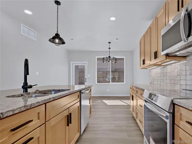 a kitchen with stainless steel appliances granite countertop a sink a stove and a wooden floor