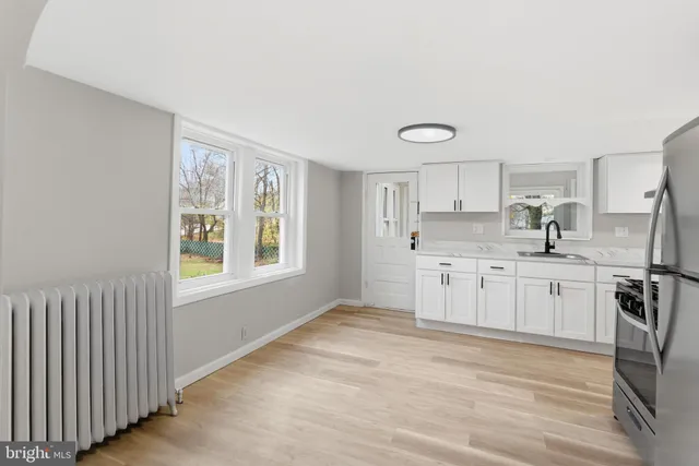 a kitchen with stainless steel appliances granite countertop a stove a sink and white cabinets with wooden floor